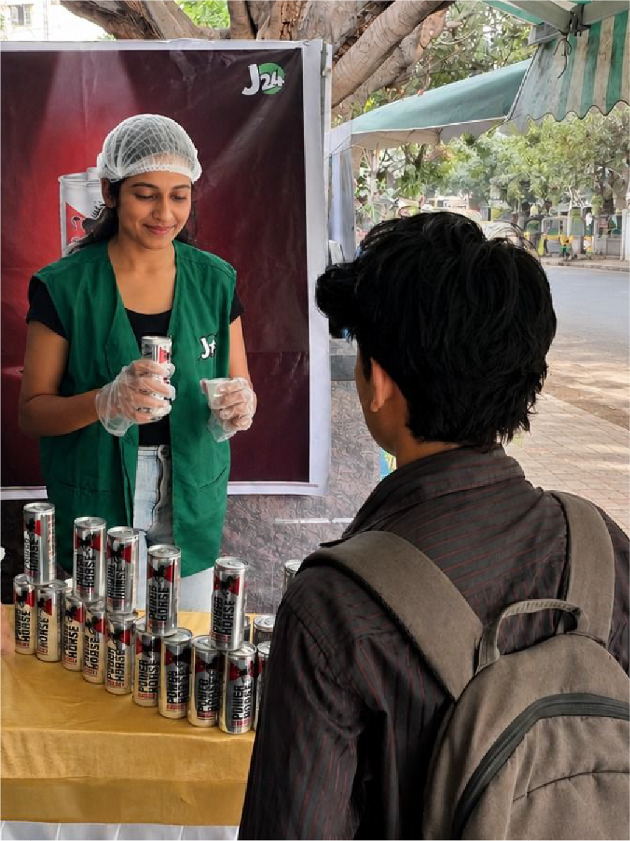 A J24 promoter offering Power Horse samples to customers outside a store