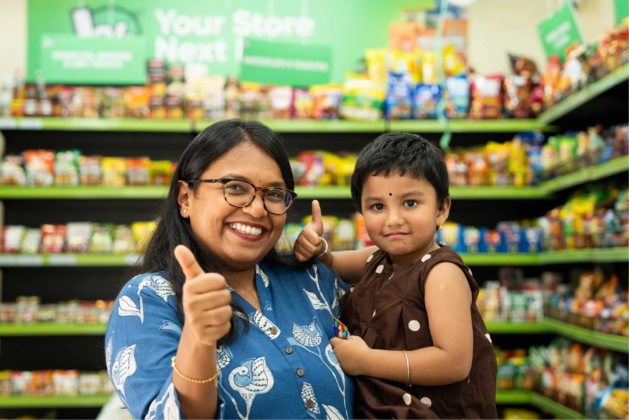 A mother and her daughter giving a thumbs up in the store aisle